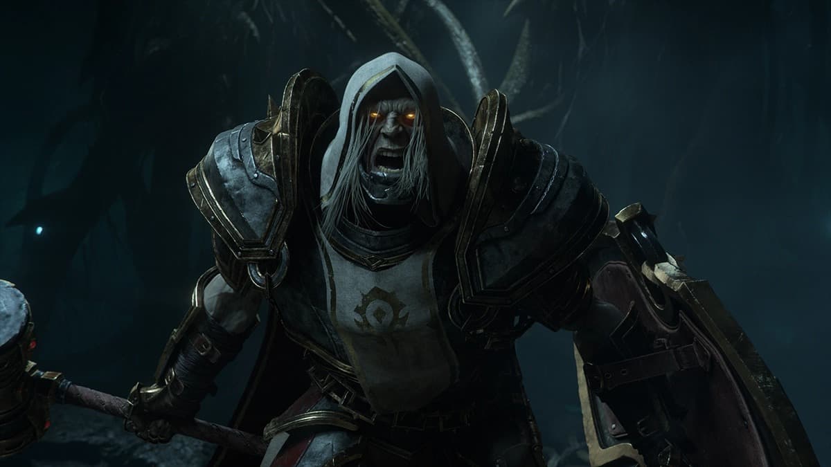 Un paladin mort-vivant de la Horde, capuche et yeux lumineux, hurle en avançant avec un marteau et un bouclier dans une grotte sombre