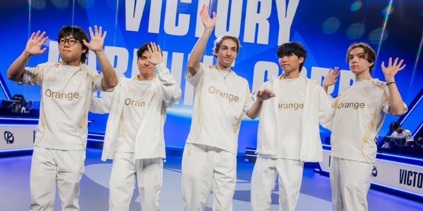 Les cinq joueurs de la Karmine Corp, en tenue blanche, saluent de la main devant l'écran « Victory » du Play-In des Worlds 2026